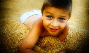 Cute boy playing in corn seeds